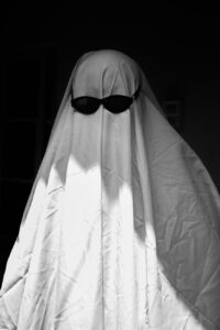 Black and white photo of a person dressed as a ghost wearing sunglasses