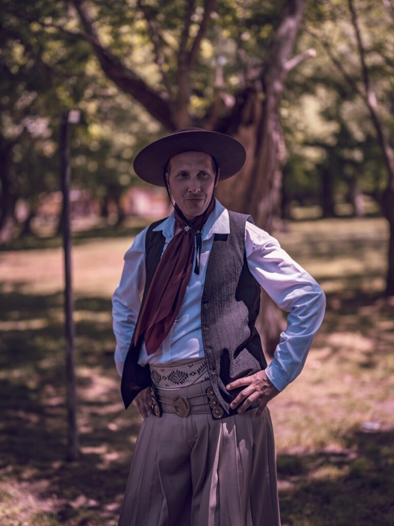 Man in traditional gaucho attire standing outdoors in a park.