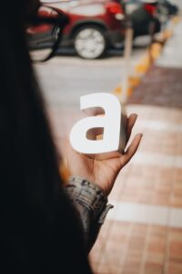 Person holding white letter “a” cutout outdoors near (Incomplete: max_output_tokens)