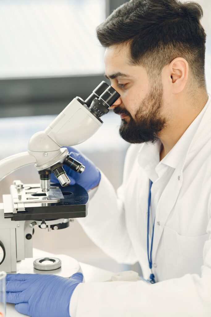 Scientist examining samples under a microscope in a genetics lab.