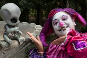 Person in colorful clown costume posing outdoors beside small alien (Incomplete: max_output_tokens)